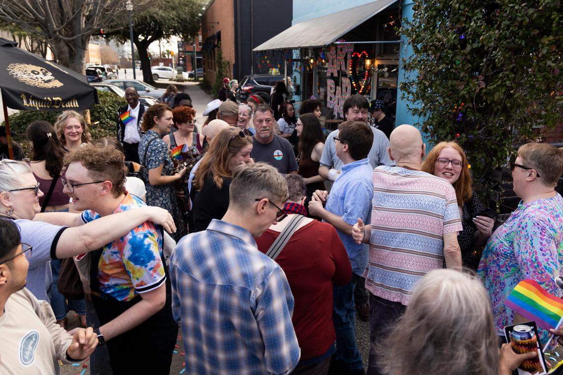 Friends and family embrace William Bonney and James Carpenter after their wedding at Y’all-Mart, a quarterly art fair series, at Art Bar in Columbia, South Carolina on Sunday, February 9, 2025. Bonney and Carpenter say they are unsure about their future legal protections and wanted to marry quickly to protect themselves.