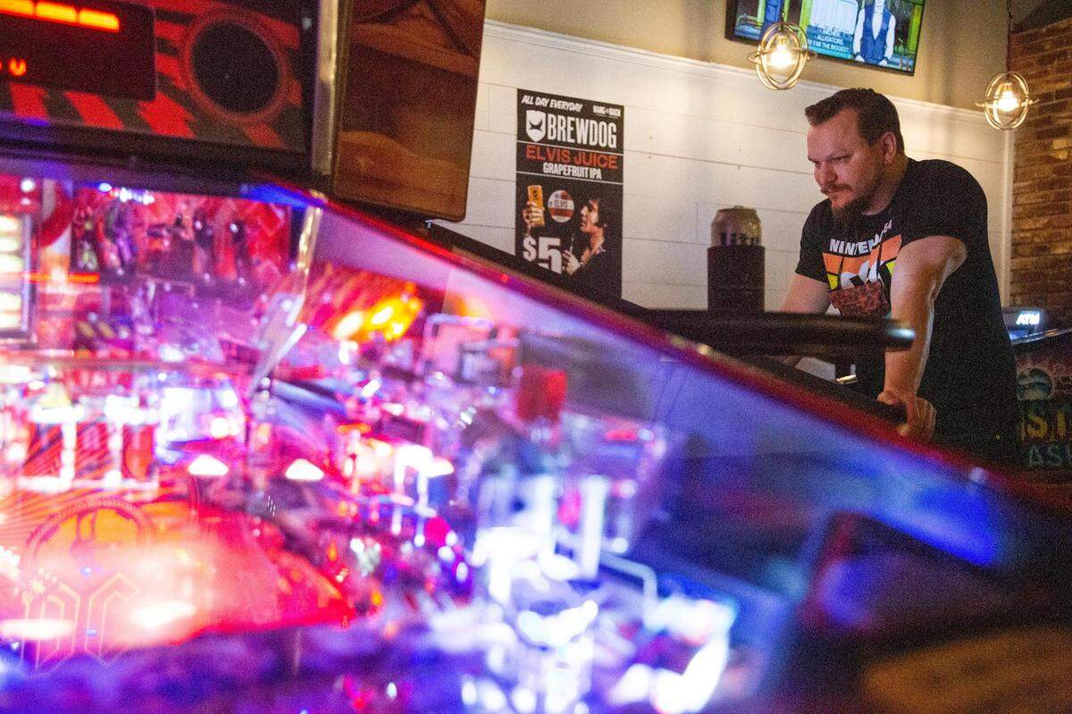 The State Newspaper’s Travis Bland plays an Iron Maiden themed pin ball machine at Bang Back Pinball Lounge on Thursday, July 15, 2021. After this image was taken, Bland soundly defeated The State visual journalist Joshua Boucher in a multiplayer game.