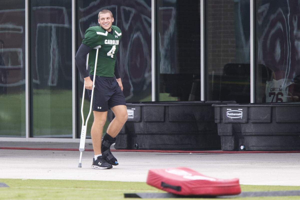 Luke Doty watches practice Aug. 25, 2021. He wore a protective boot and used one crutch while meeting with teammates. 