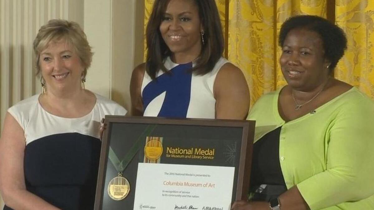 First Lady Michelle Obama laughs as she presents Karen Brosius, left, and Joyce Rose-Harris from the Columbia Museum of Art with a 2016 National Medal for Museum and Library Service award during a Wednesday ceremony at the White House. Rose-Harris, a longtime CMA patron, was invited to talk about how CMA has affected her life.