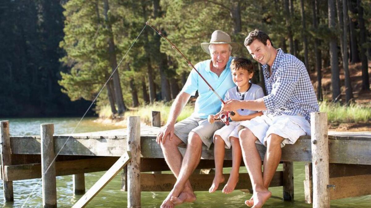 Father, son and grandson fishing together sitting on pier