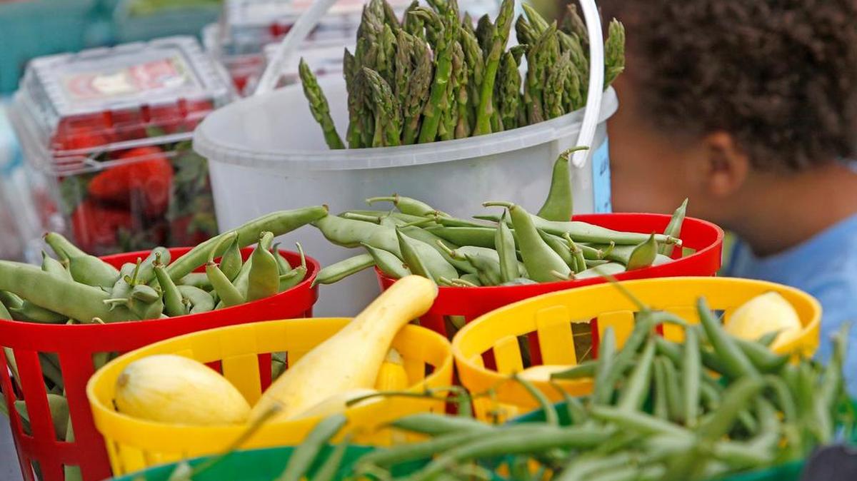Checking out produce at a past Lexington farmers market. This year’s market opens early in May.