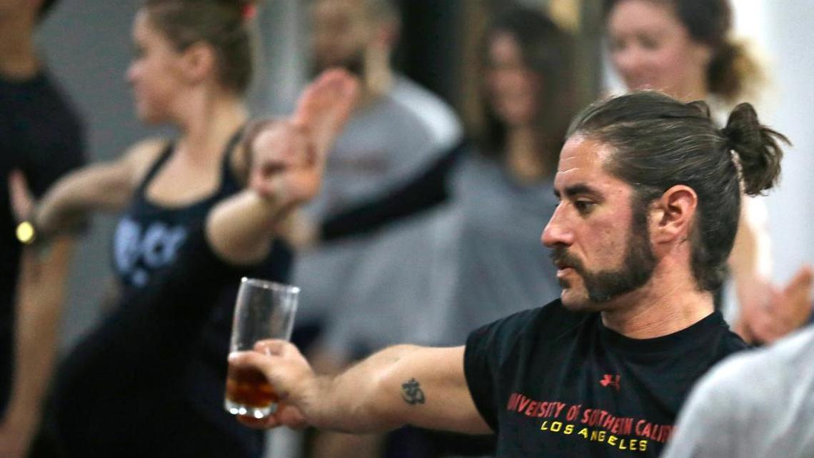 In this Thursday, Dec. 3, 2015 photo, Reed Patterson practices yoga while holding onto his beer at the Platform Beer Co., in Cleveland. Craft breweries are partnering up with yoga studios around the country as more breweries are hosting classes to attract a new crowd to the bars and yoga studios are using the beer to get more men to try yoga.
