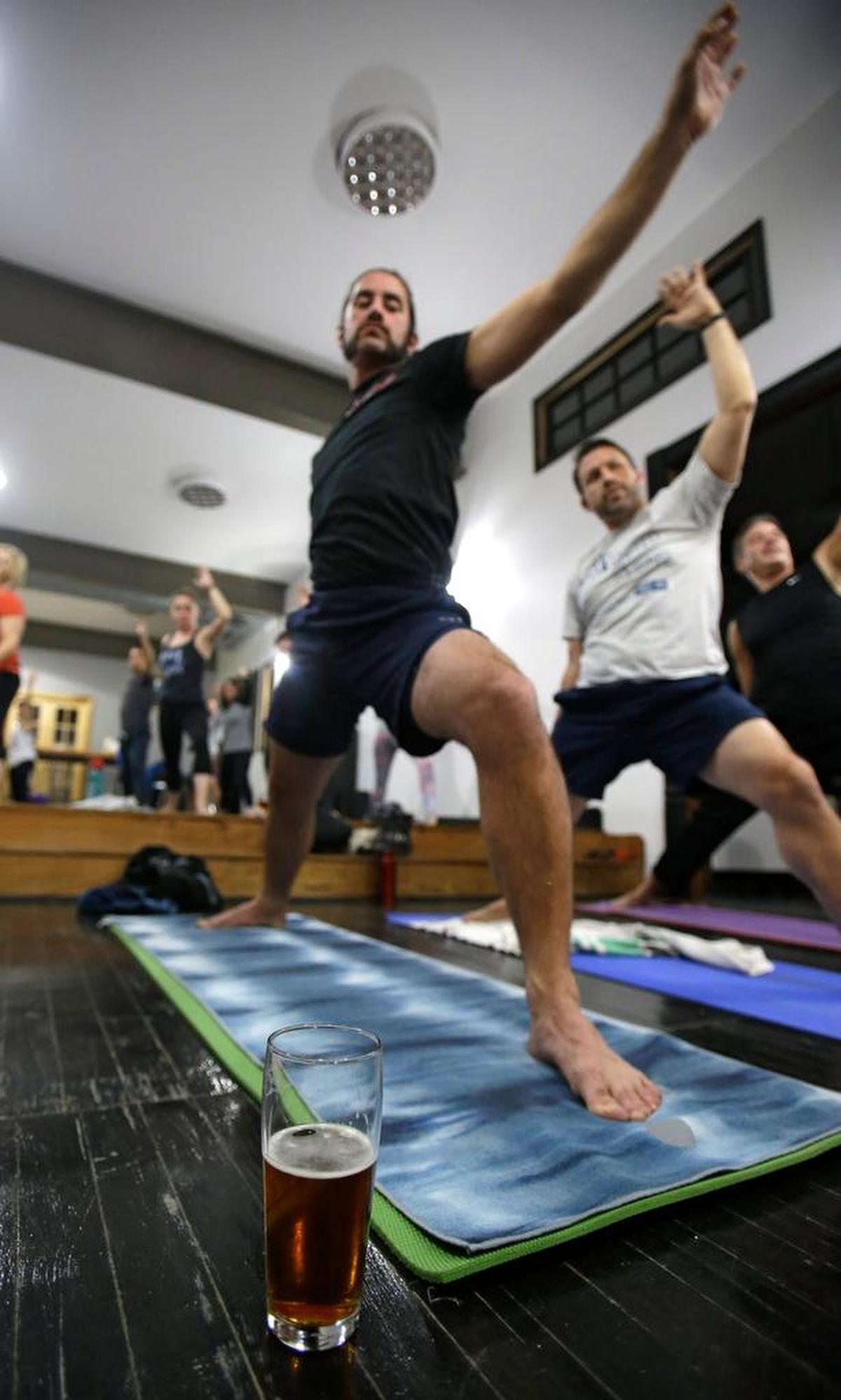 In this Thursday, Dec. 3, 2015, Reed Patterson practices yoga next to a beer at the Platform Beer Co., in Cleveland. Craft breweries are partnering up with yoga studios around the country as more breweries are hosting classes to attract a new crowd to the bars and yoga studios are using the beer to get more men to try yoga.