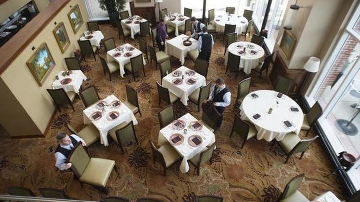 Servers set tables in preparation for the dinner crowd at Halls Chophouse in downtown Greenville.