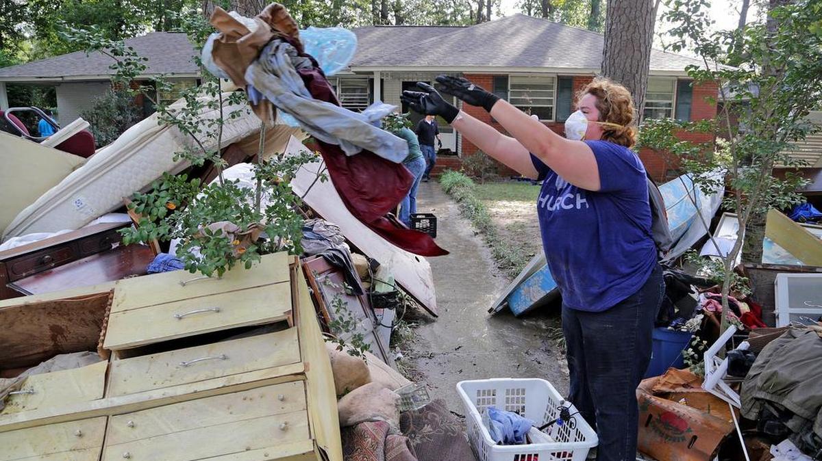 
Courtney Pressley, of NewSpring Church, helps discard flood damaged items Friday from a residence on Glenhaven Drive. 
