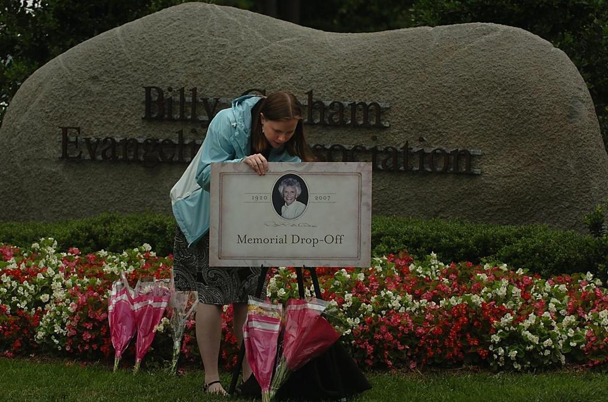 In June 2007, Laura Cochran, an employee with the Billy Graham Evangelistic Association, arranges flowers and a memorial drop-off sign at the entrance of the Billy Graham Library in Charlotte the day after Ruth Graham died.