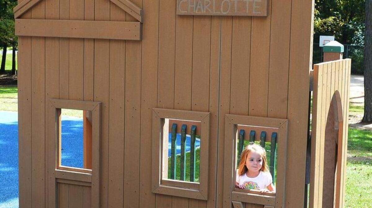 
A girl plays on the children's playground at Park Road Park around a replica of a general store with a red cross emblazoned on the front on Monday. The county removed the cross when a Charlotte mother said she found it ostracizing and offensive.
