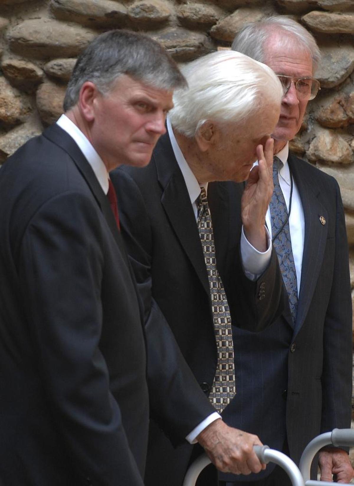 Evangelist Billy Graham, center, wipes his eye as he leaves the service with his son, Franklin Graham, left, following the funeral for Ruth Graham in Montreat in 2007, in Montreat.