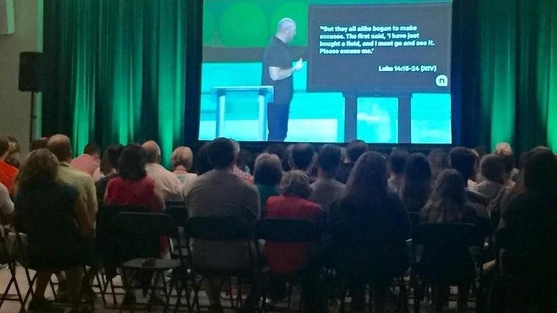 More than 100 NewSpring members attend the late morning satellite service at Ravenel Elementary School in Seneca. They watched Interim Senior Pastor Clayton King, pictured on screen, preach Sunday from the Anderson campus about the need for the church's members to re-engage on a personal level with others, especially those from different paths of life.