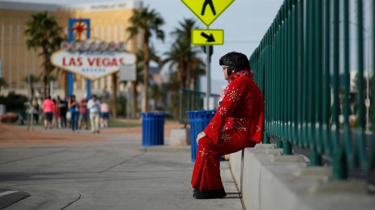 In this March 3, 2016, photo, Ted Payne rests as he works for tips dressed as Elvis at the "Welcome to Las Vegas" sign in Las Vegas. For decades, Las Vegas has loved Elvis Presley. But the King's presence in modern day Sin City has lately been diminishing.