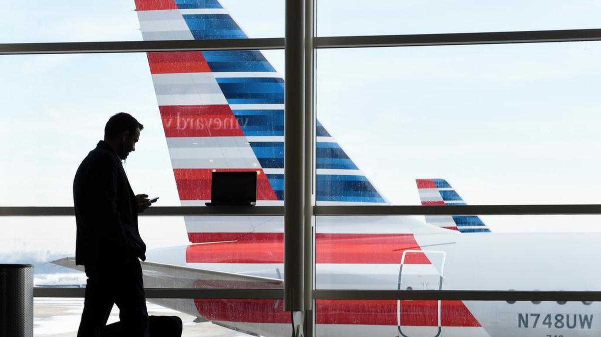A passenger talks on the phone as American Airlines jets sit parked at their gates at Washington's Ronald Reagan National Airport. American Airlines announced Wednesday, Jan. 18, 2017, that passengers will be able to buy “basic economy” tickets starting in February.