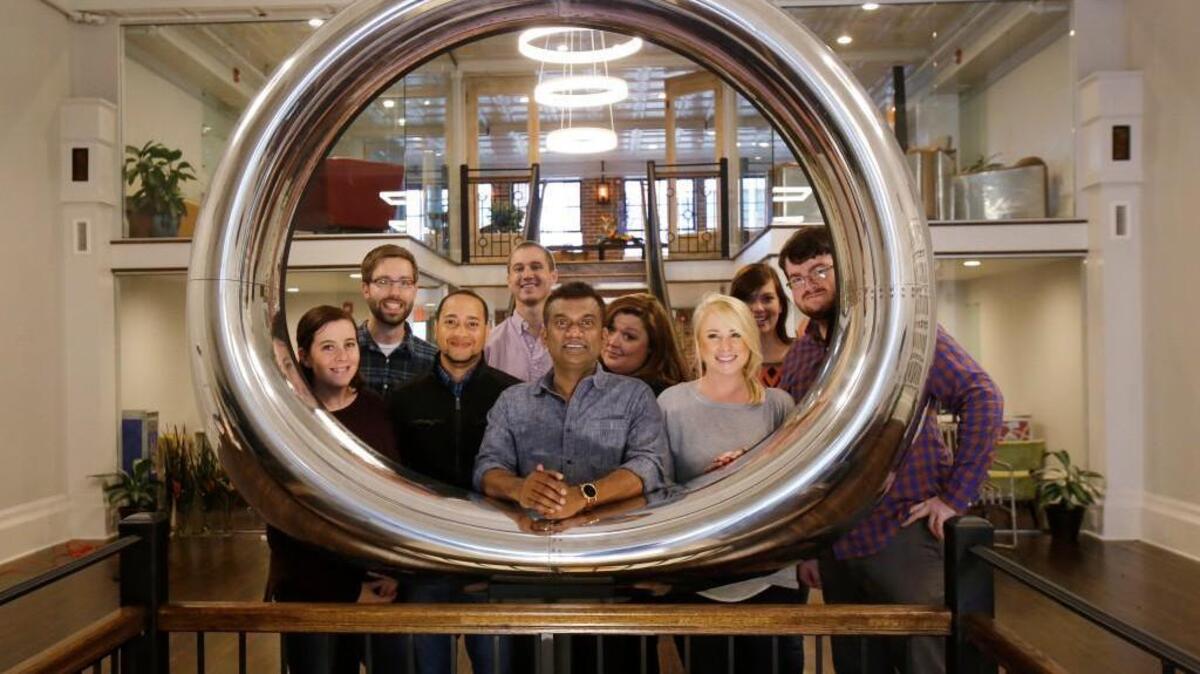 Agie Sundaram, co-owner of Span Enterprises, shows the company's new office in downtown Rock Hill. Sundaram, center, and his staff are framed by an engine cowling from a Boeing 737 jet..