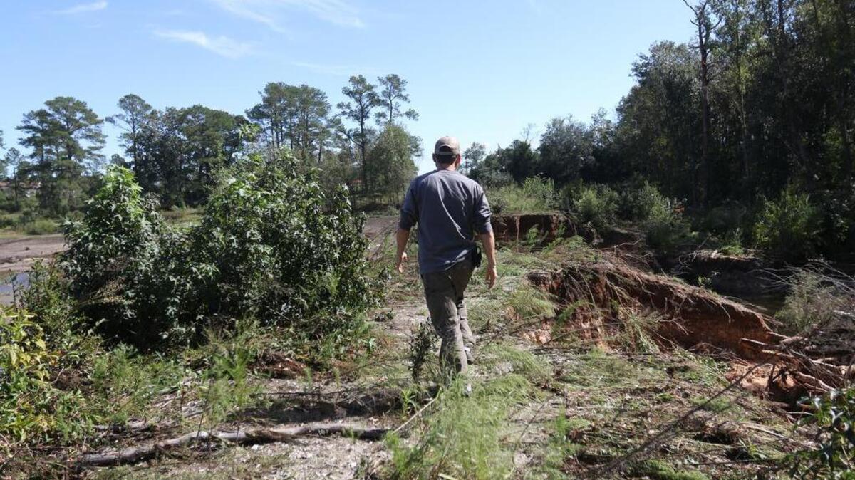 Jason Carter looks at a breached dam near his farm in Eastover.