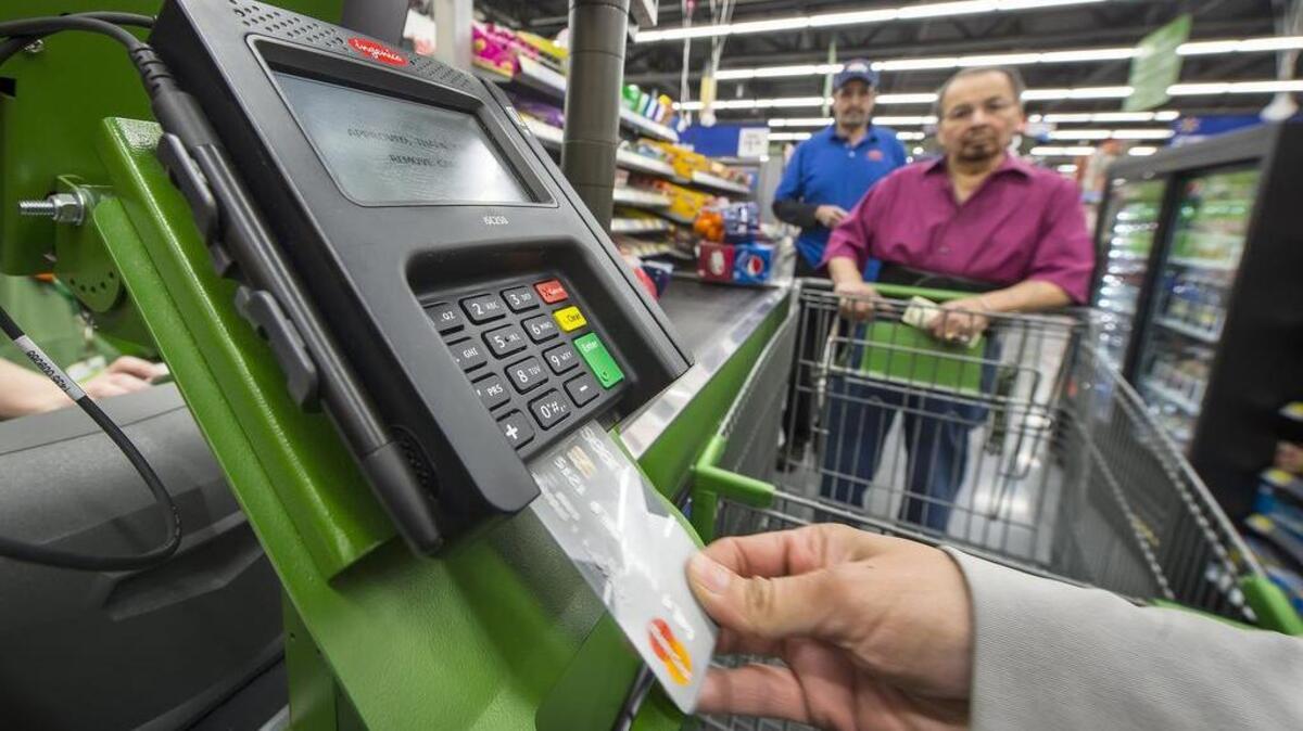 
A customer uses her microchip-embedded credit card in a card reader at a Wal-Mart Neighborhood Market in Kansas City. 
