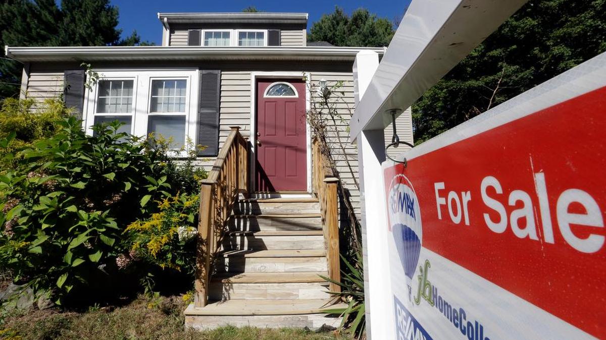 A for sale sign hangs in front of a house