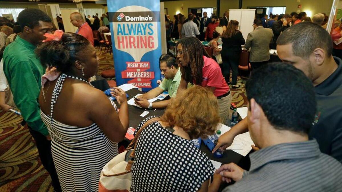 
In this photo taken Wednesday, July 15, 2015, job seekers listen as Kaysara Mandry, center, talks about job opportunities at the Domino's booth during a job fair in Miami Lakes, Fla. U.S. hiring slowed sharply and previous job gains were revised lower amid a broad slowdown in the global economy
