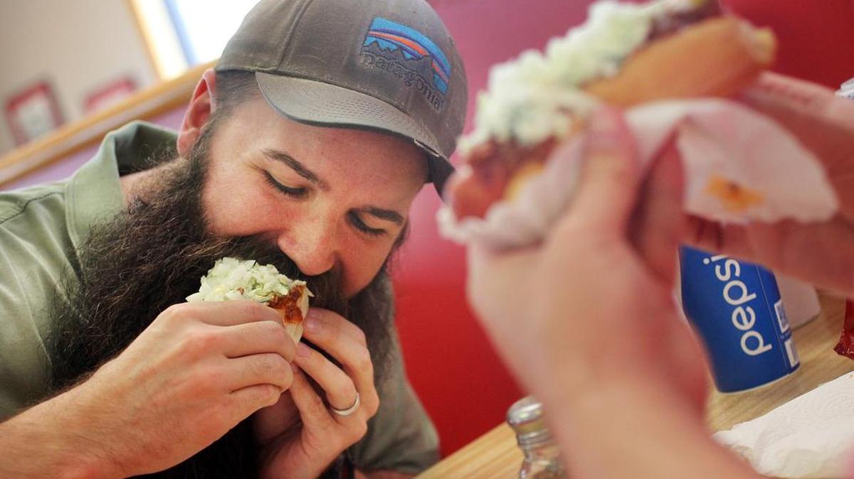 Wayne Fischer and his brother Adam enjoy two of Sandy's Famous Hot Dogs at the Main Street location on Friday. The store is near the USC Horseshoe .
