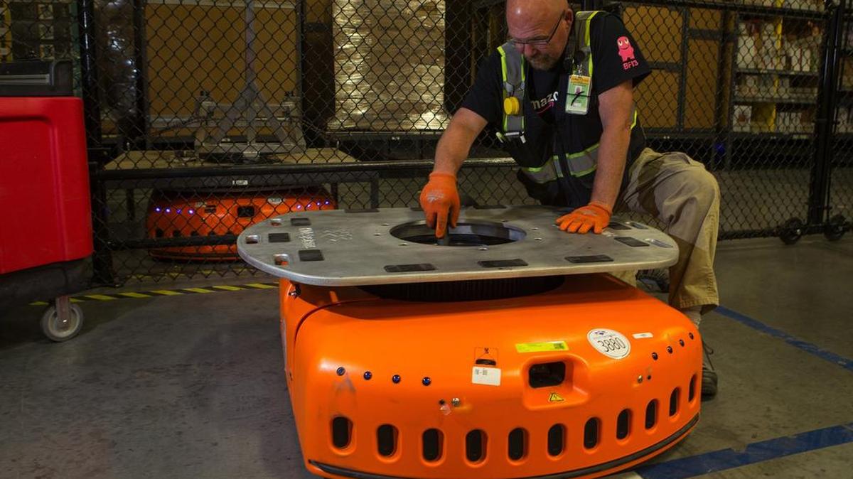 Barry Tormoehlen, a maintenance technician at Amazon’s fulfillment center in DuPont, vacuums the inside of a KIVA, one of Amazon’s robots that are used to move items around the center. The KIVAs weigh 800 pounds each and can carry up to 3,000 pounds of merchandise.