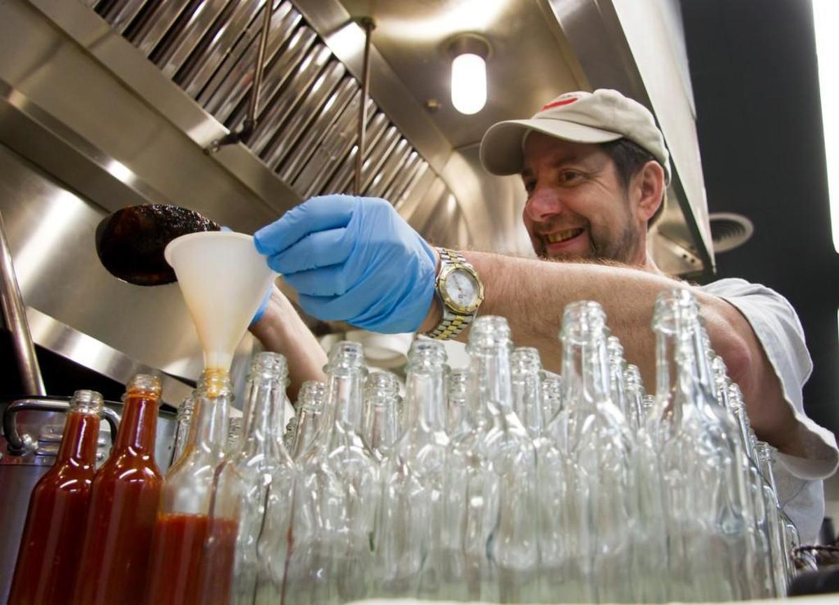 Ed Currie, owner of PuckerButt Pepper Company, pours bottles of hot sauce at the Fort Mill business in this Herald file photo.