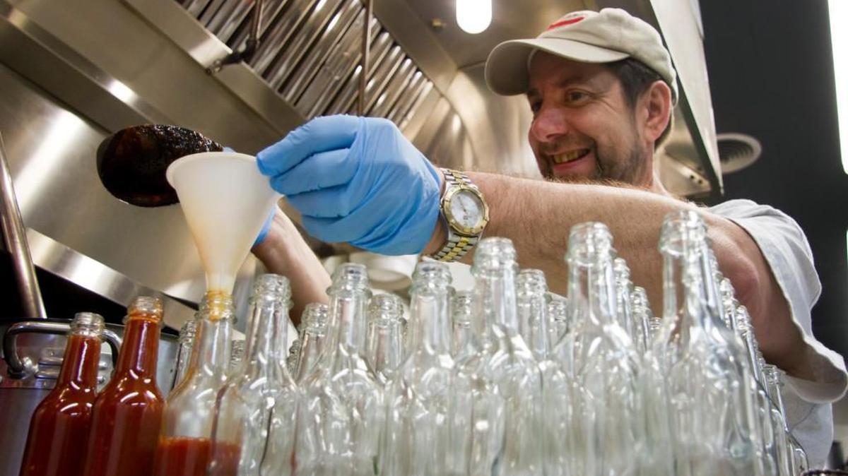 Ed Currie, owner of PuckerButt Pepper Company, pours bottles of hot sauce at the Fort Mill business in this Herald file photo.
