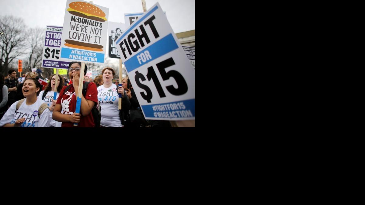 Protesters display signs and chant slogans Tuesday during a rally, in Boston. Organizers call for the lowest paid workers to earn at least $15 an hour.