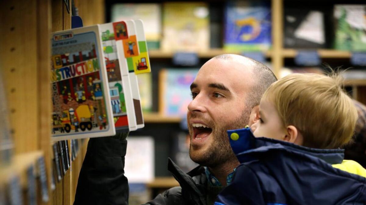 Michael Wallenfels looks at children's books with his son Henry, 2, at the opening day for Amazon Books on Tuesday in Seattle.