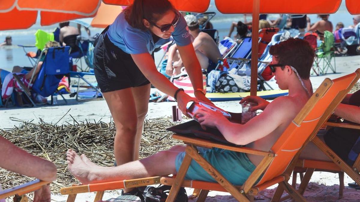 A server with Sea Pines’ Beach Club delivers a meal to vacationer Micah Abramson, sitting in a roped-off section of beach on Wednesday.