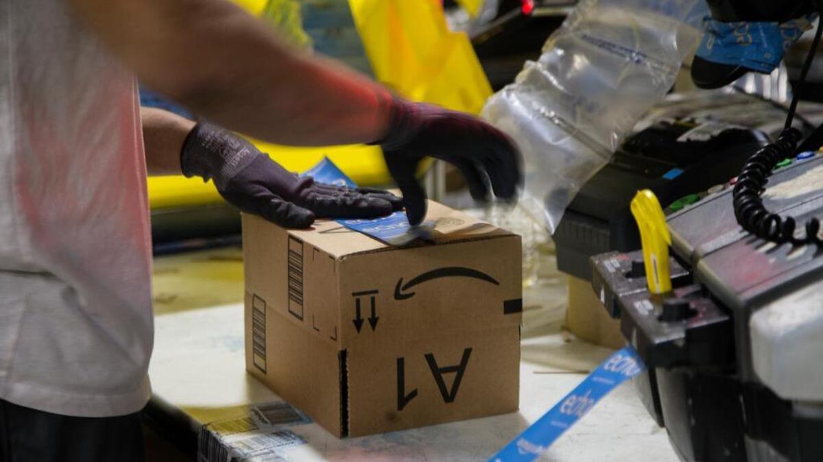 A worker tapes a box while packing items at the Amazon Fulfillment Center in San Bernardino, Calif.