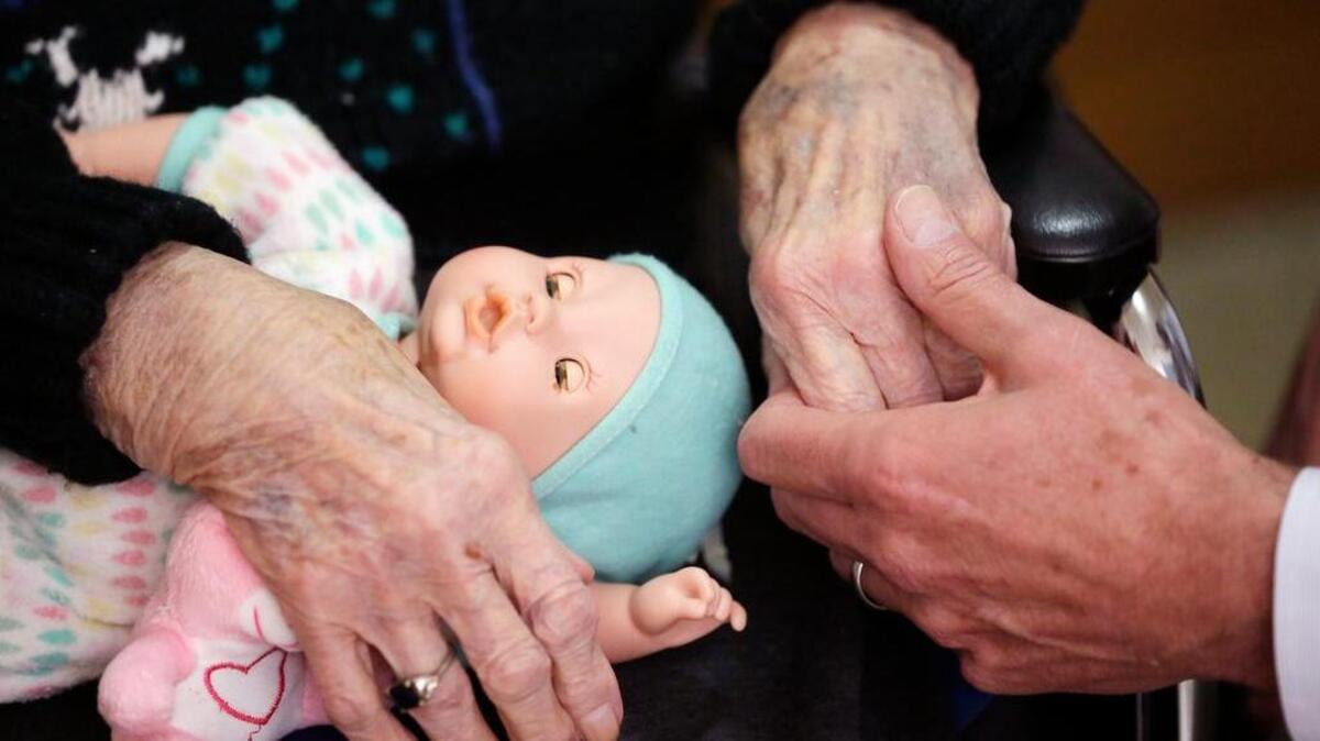 A son, at right, holds his mother’s hand as they talk at her nursing home in Adrian, Mich. Long-term care costs are still rising and the most expensive option, a private nursing home room, may soon top $100,000 per year.