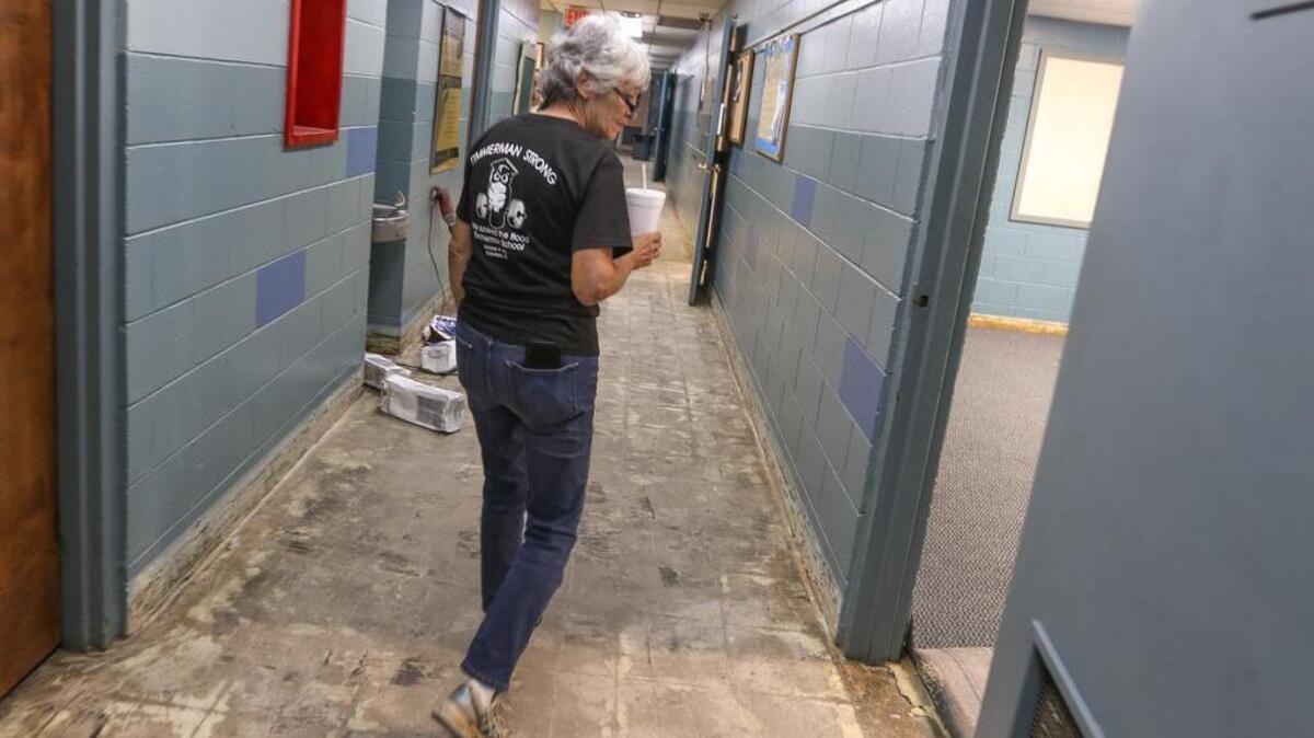 Principal Liz Jordan walks down a hallway where tile needs to be replaced in the Timmerman School. The school flooded during the recent storms.