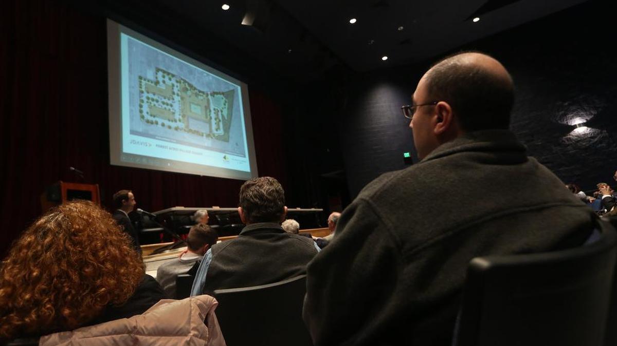 Maher Nassri and others watch a presentation during a public hearing to discuss the future plans for the former Cardinal Newman High School property on Forest Drive