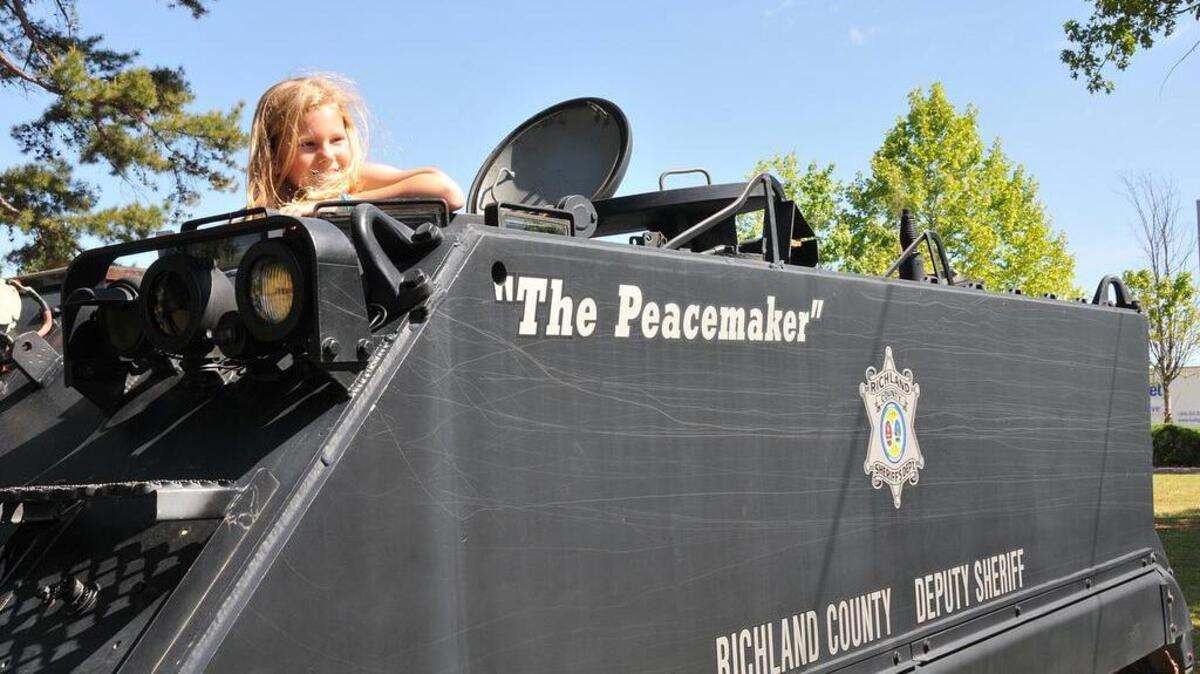 Hayley McCabe of Irmo peeks out of the top of the Peacemaker during the Eau Claire Festival in Hyatt Park on April 26, 2014. The Peacemaker is an armored personnel carrier used by the Richland County Sheriffs Department. Sheriff Leon Lott says the tank is popular with children and adults alike.