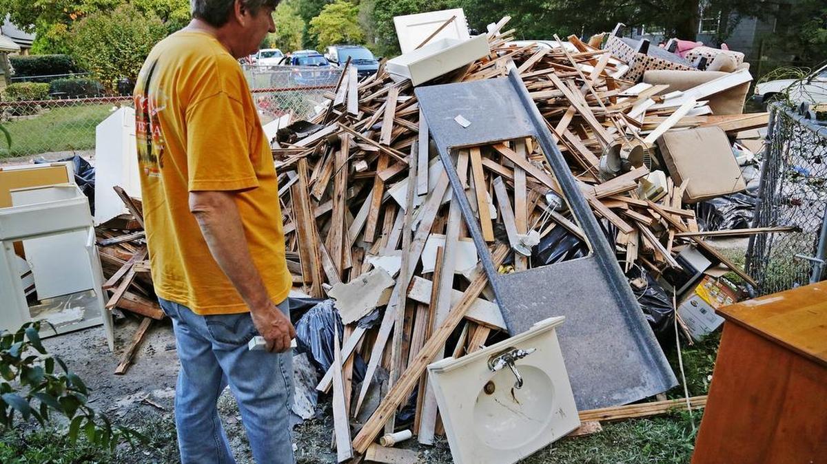 
State newspaper reporter Jeff Wilkinson looks at some of the flood-damaged items from his home on Downing Street. The home was overtaken by flood waters and Wilkinson had to swim to safety.
