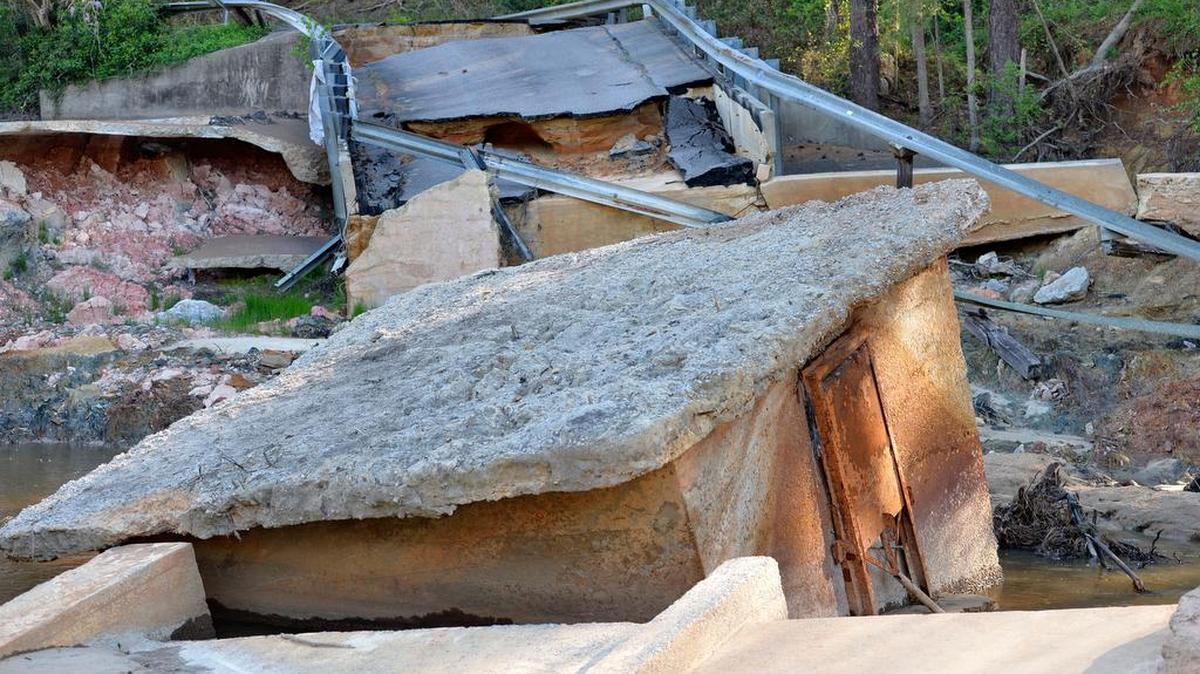 This Wednesday, March 30, 2016 photo shows a portion of the crumbled remains of the Cary Lake Dam in the community of Arcadia Lakes in Columbia, S.C. Heavy rains and floods topped the dam, eating away at its earthen sides and collapsing the road on top of it. (AP Photo/Richard Shiro)