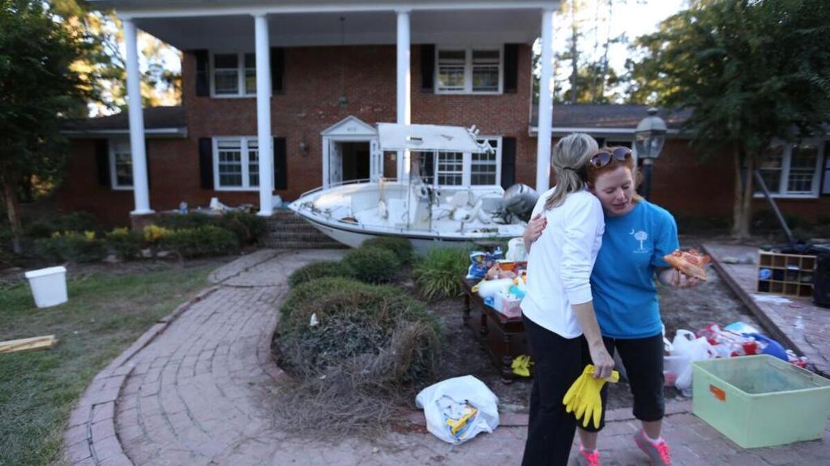 
Beverly Steinhaus hugs Carol Hill, a friend who helped clean her house on Burwell Street after it was submerged in floodwater.
