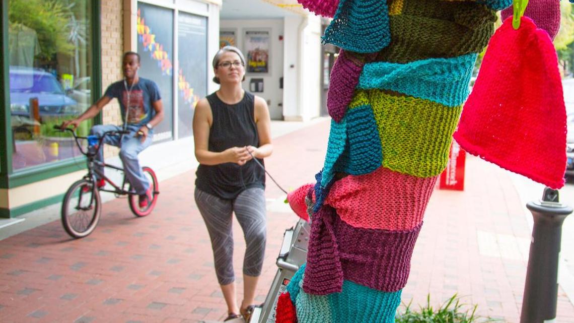 Rachael Giglio hangs knitted pieces on the “giving tree” on Columbia’s Main Street. The tree is part of a yarn-bombing project along the 1500 and 1600 blocks of Main.