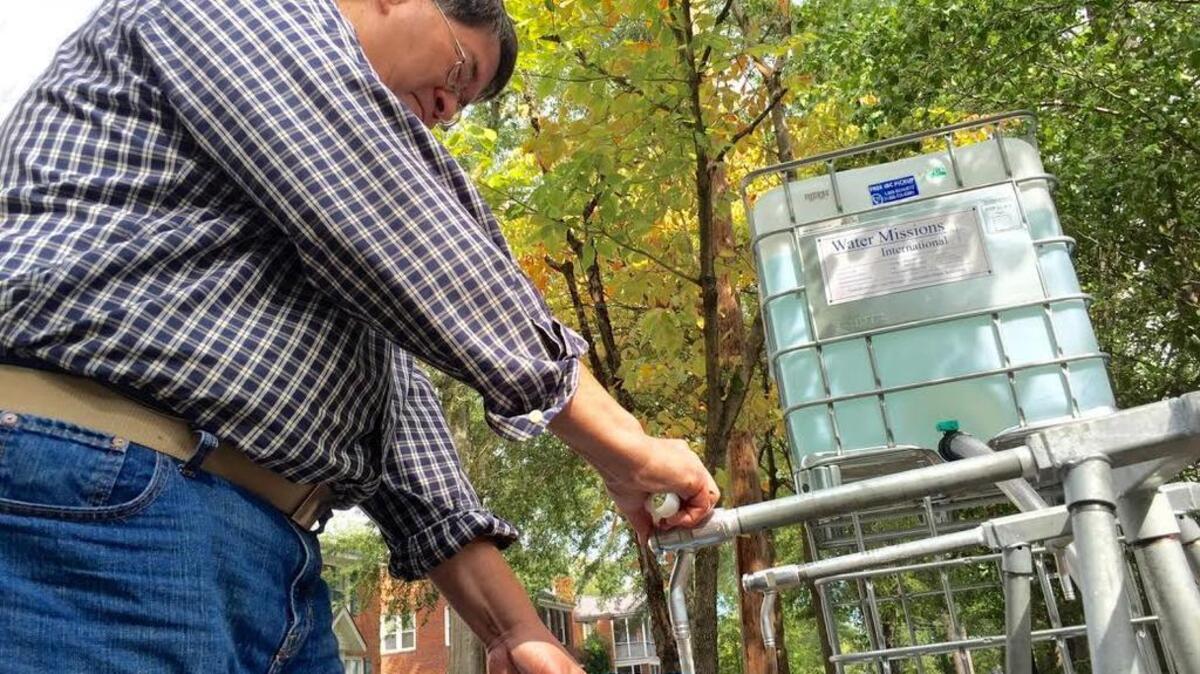 
Ken Easley fills up a container with clean water at 1522 Gladden St. on Friday.
