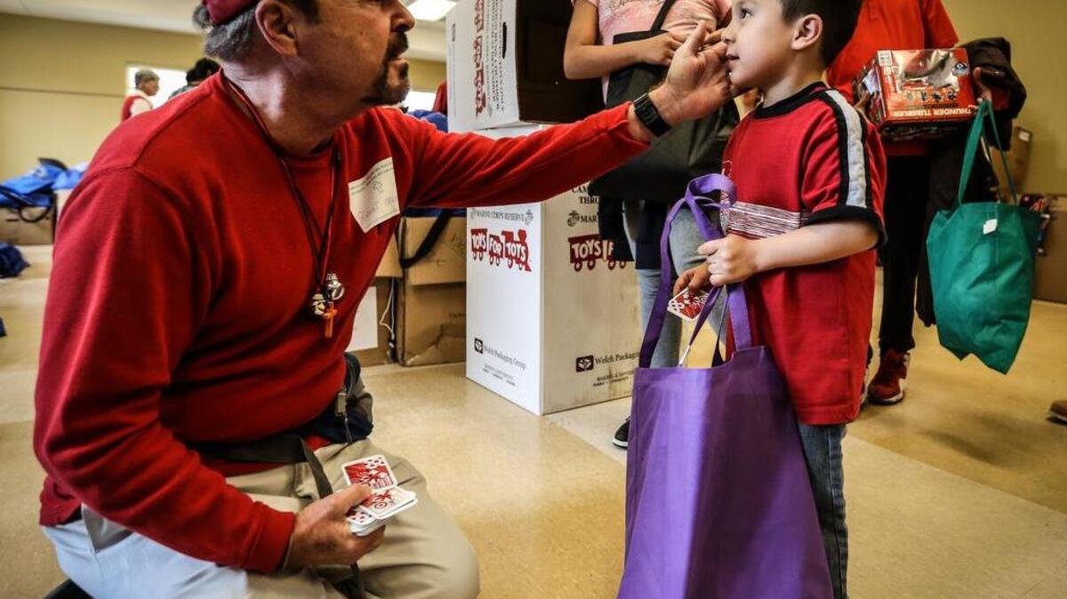 Robert Keeder gives Angel Castro a target gift card for Christmas after lunch. Parishioners and volunteers at St. Peter’s Catholic Church served lunch to hundreds of homeless on Christmas Day. They also gave toys, clothes and gift cards to children. The church has served Christmas Day lunch for 30 years.