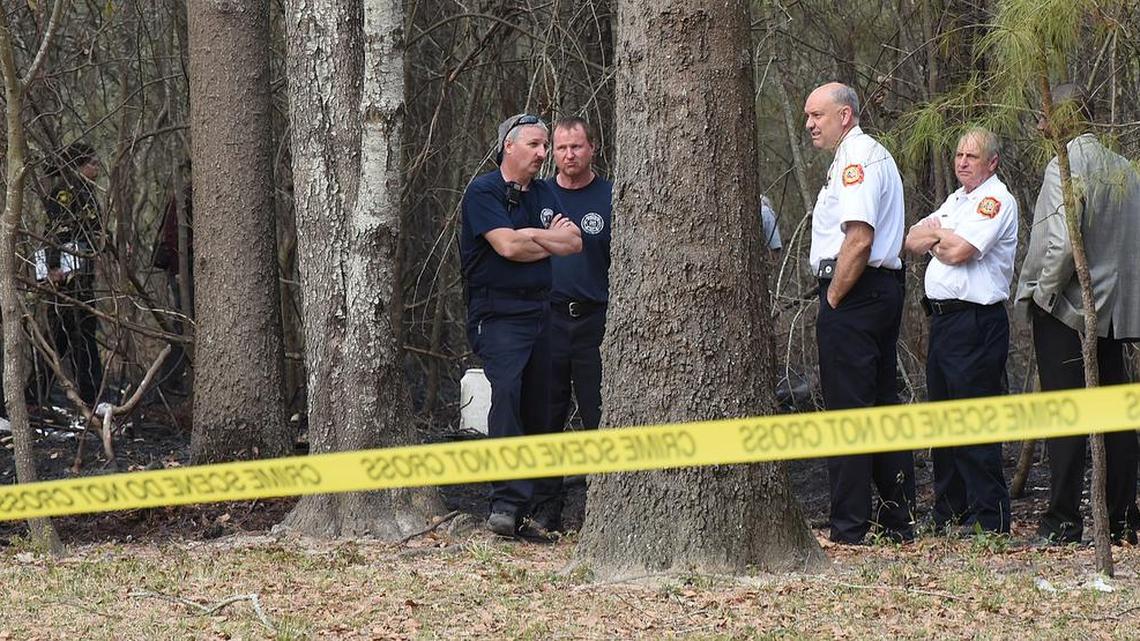 Sumter Fire Department officials look over the scene where an elderly woman was found dead after possibly catching her clothing on fire and running through the woods.