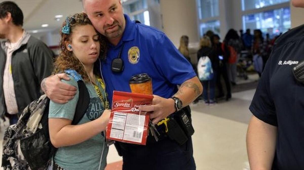 A student gives Tony Koutsos, a school resource officer at Mauldin High School, a hug before classes start on Nov. 6, 2015.