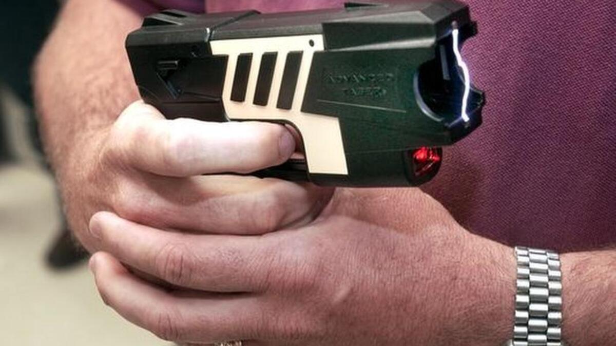 Greenville police Sgt. Mark Hunington demonstrates the electric current that flows from this Taser through wires and into the person being subdued. In this case the wires are not connected so the current flows back into the gun. STAFF photo by Owen Riley Jr. 5/10/04