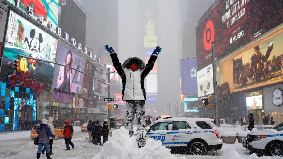 Bella Fraker, 10, of Atlanta, stands high on a snow pile as she poses for a family photo in New York's Times Square. New York City and other cities in the mid-Atlantic began digging out after the storm.