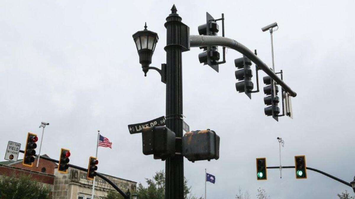 Cameras on traffic poles feed vehicle flow information to computers controlling signals, deciding how long lights stay green to minimize backups.