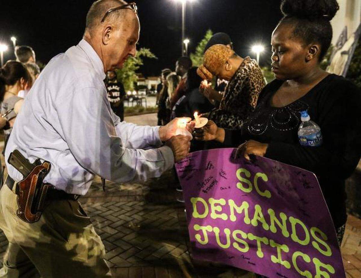 Charleston County Sheriff Al Cannon lights a candle at a rally for Walter Scott in front of the North Charleston City Hall on Wednesday night. Organizers from various activist groups planned rallies and demonstrations in the wake of the shooting death of Walter Scott by a North Charleston police officer.