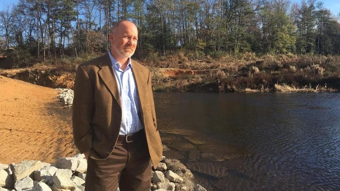 Laban Chappell, partner in a Lowcountry firm that owns the Old Mill Mall in Lexington, looks over a temporary wall in an adjoining empty pond. Rebuilding the pond dam that ruptured in a storm 14 month ago is in limbo.