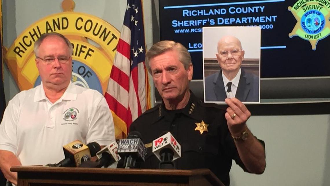Sheriff Leon Lott, right, holds up a picture of 81-year-old Duaine Hamilton, a Sears employee at Columbia Place Mall who was killed when he tried to stop two shoplifters from stealing TVs from the store last week.