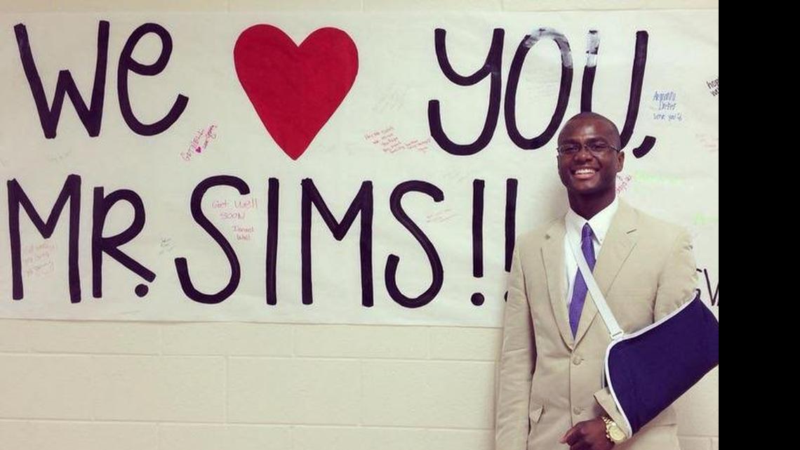 
Sims at the school in front of a banner made by students
