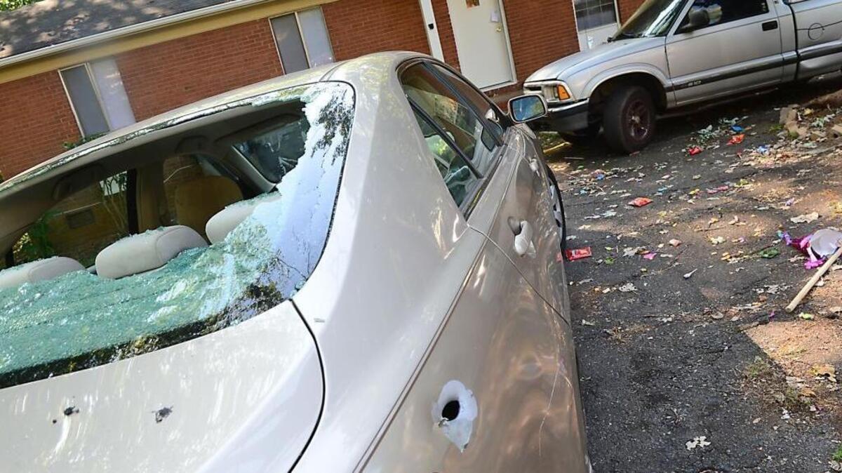 
A bullet-riddled car and candy spilled from a  piñata are visible outside a home on Fieldvale Place in southwest Charlotte on Sunday. A 7-year-old boy died after being shot during a party at the home.
