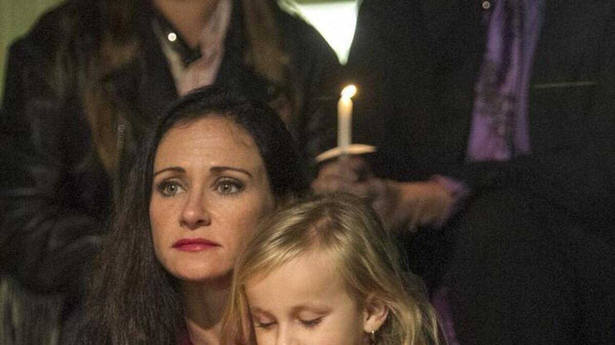 Carrie Dunn sits with her 5-year-old daughter, Ella, during a candlelight vigil for 'Baby Grace' on Saturday, November 14, 2015. Dunn, a representative of Bethany Christian Adoption Services spoke about forgiveness to the gathering of about thirty people at the Calvary Christian School. The body 5-month-old Grace Carlson Santa Cruz was found in swamp waters after a three day search. Baby Grace's mother, Sarah Lane Toney, 33, said she lost the infant in the rushing creek after entering the water near her Simms Drive residence last Tuesday. Toney is charged with Homicide by Child Abuse.